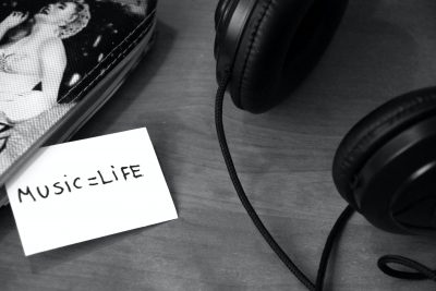 grayscale photo of printer paper with printed music life near headphones